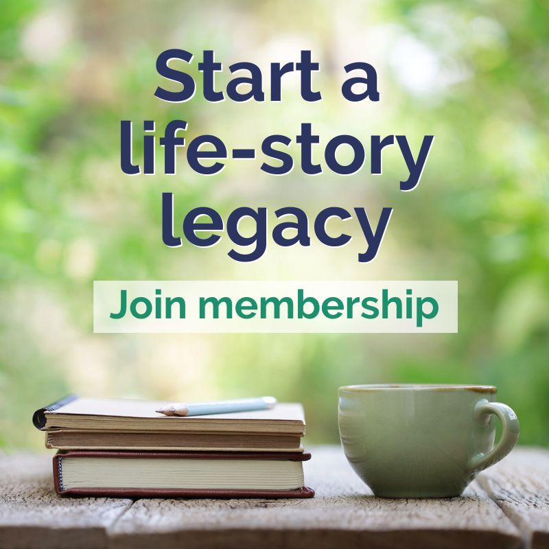 Forever Young Autobiographies Membership. A pen, books and a mug sit on a wooden table outside.